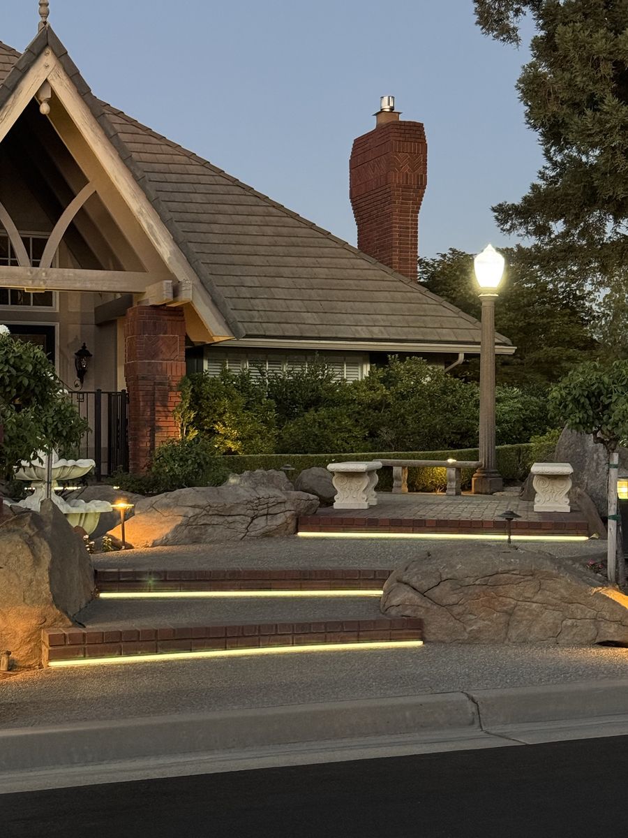 LED strip lighting under brick steps at dusk in front of a home